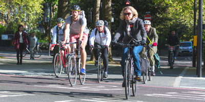 People cycling down a busy street.