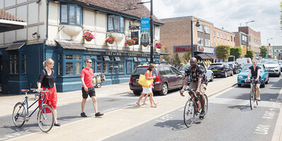 A busy high street with mixed traffic moving at safe speeds