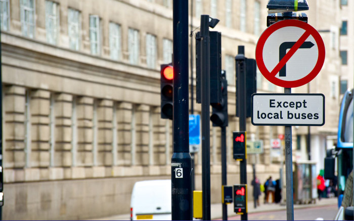 A red and white 'banned turn' road sign with a diagonal line through a turning arrow